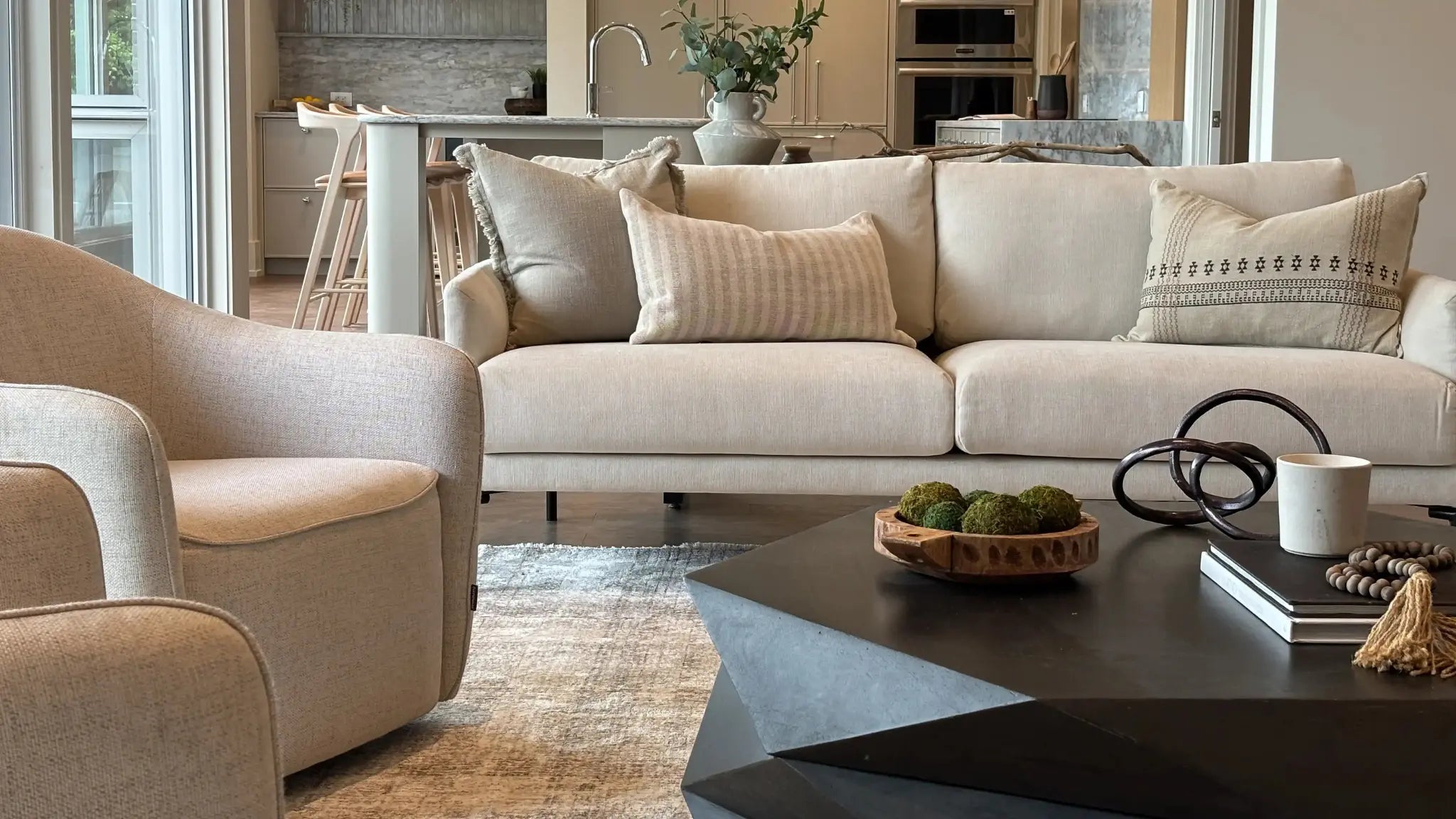 Modern living room with beige sofa, armchair, and coffee table.